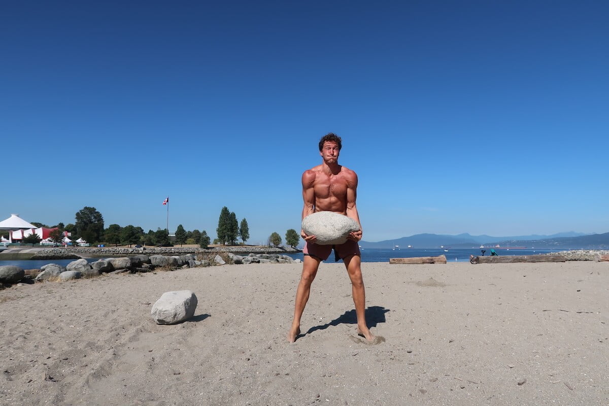 Chris lifting a big rock at the beach.