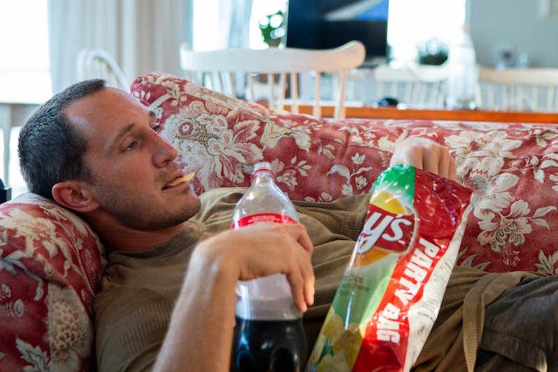 Character missing direction in life eating chips and drinking soda